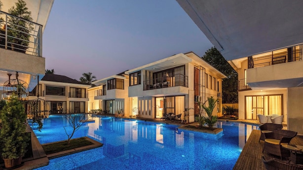 A modern hotel with a swimming pool, outdoor seating, and balconies. - Staymaster Aurum Aqua 3BR Villa  (Vagator)