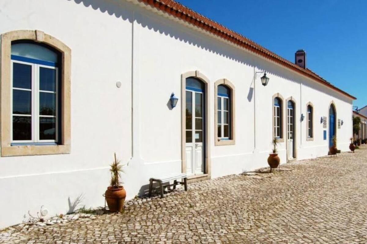 A white building with arched windows and a cobblestone courtyard.