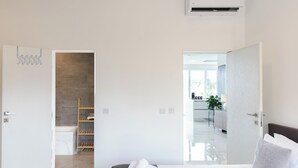 Una habitación de hotel moderna con cama, baño con ducha y vistas a la cocina y la sala de estar.