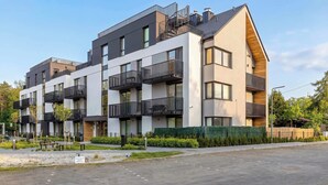 A modern multi-story residential building with balconies, a paved driveway, and landscaped areas. - Secluded Studio in Gdansk | Private Parking and Balcony (Gdańsk)