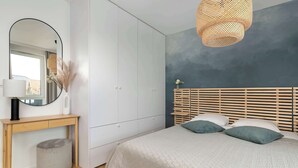 A bedroom with a bed, bedside table, mirror, and a hanging light fixture. - Secluded Studio in Gdansk | Private Parking and Balcony (Gdańsk)