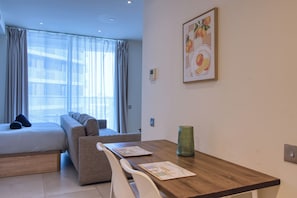 A hotel room with a bed, a sofa, a dining table, and a green vase. - New! Luxury Central Complex with Pool Access & Sleeps 4 People (Gibraltar)