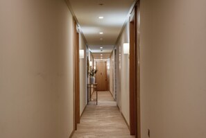 A long, narrow hallway with wooden doors on either side, recessed ceiling lights, and a small table with a vase of flowers in the center. - New! Luxury Central Complex with Pool Access & Sleeps 4 People (Gibraltar)
