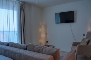A modern living room with a sofa, armchair, TV, and lamp. - New! Luxury Central Complex with Pool Access & Sleeps 4 People (Gibraltar)