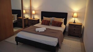 A bedroom with a large bed, two bedside tables with lamps, a mirror, and a wardrobe. - Beachfront Bliss in Praia Baixo – 1Min Walk to Sea (Praia Baixo)