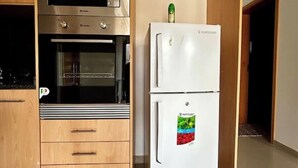 A kitchen with a microwave, oven, and a refrigerator with a sticker. - Beachfront Bliss in Praia Baixo – 1Min Walk to Sea (Praia Baixo)