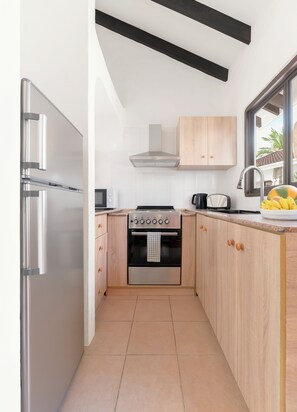 Una cocina moderna con electrodomésticos de acero inoxidable, armarios de madera y una ventana con vistas.