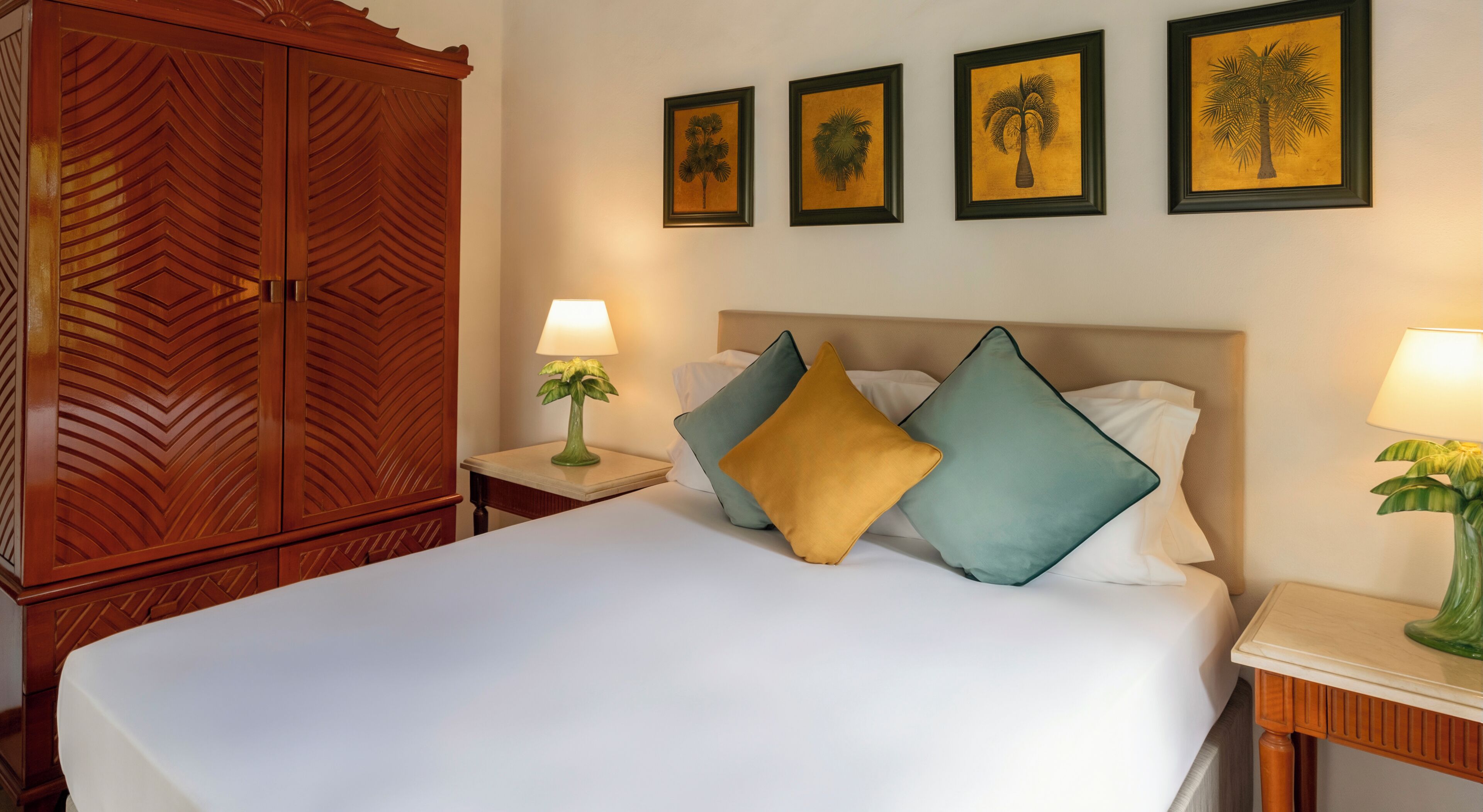 Ein Hotelzimmer mit einem großen Bett, einem Holzschrank und drei gerahmten Bildern an der Wand.