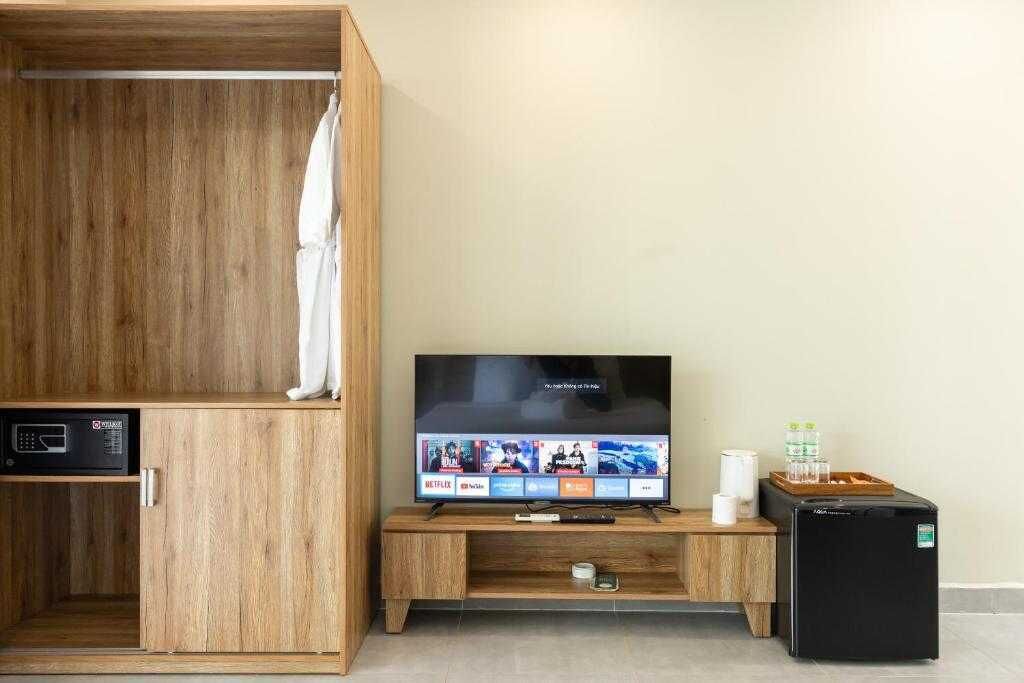 A room with a wooden cabinet, a television, a small refrigerator, and a microwave.