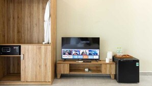 Una habitación con un armario de madera, televisor, refrigerador pequeño y microondas.