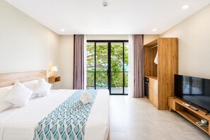 Een hotelkamer met een bed, een televisie, een houten kast en een balkon met gordijnen.