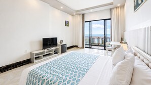 Habitación de hotel con una cama grande, televisión, cafetera, escritorio y balcón con vistas.