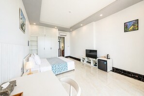 Ein modernes Hotelzimmer mit Bett, Fernseher, Minikühlschrank und Essecke.