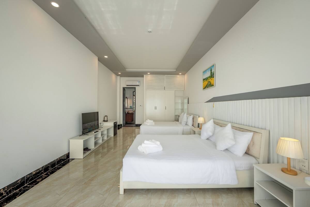 Een hotelkamer met twee bedden, een televisie, een bureau en een badkamer in de achtergrond.