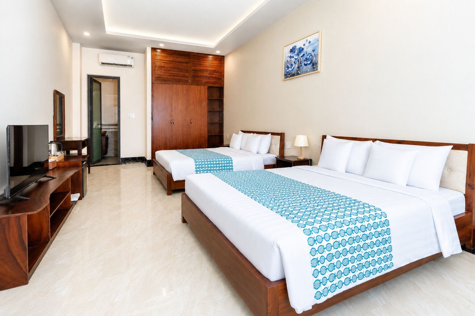 A hotel room with two beds, a TV, a desk, and a wardrobe.