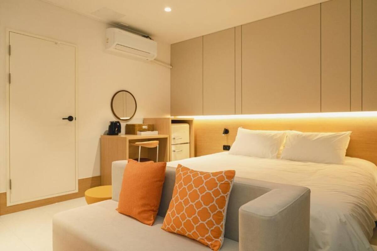 A hotel room with a bed, a desk, a chair, a small table, and a wardrobe.