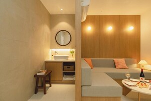 Un baño moderno con lavamanos, espejo y un pequeño taburete.