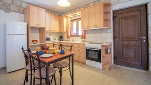 Eine Küche mit Holzausstattung, einem Kühlschrank, einem Herd und einem Esstisch mit Stühlen.