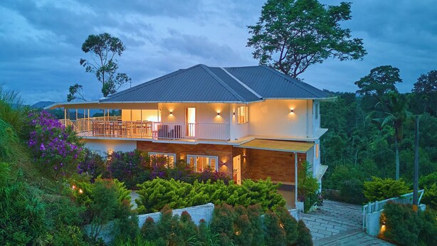 A two-story house with a balcony, surrounded by lush greenery. - Munnar Ice Pellets Resort with Pool (Devikolam)