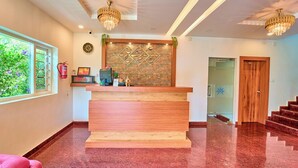 A reception area with a wooden desk, a clock, a fire extinguisher, and a staircase leading to another room. - Munnar Ice Pellets Resort with Pool (Devikolam)
