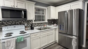 Une cuisine moderne avec des armoires blanches, un réfrigérateur en acier inoxydable, un four à micro-ondes et une cuisinière.