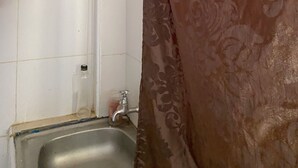 Un baño con lavamanos, grifo y inodoro.