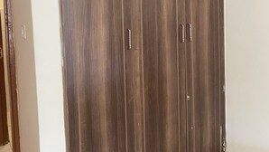 Un armario grande con dos puertas y un tirador, situado en una habitación con paredes blancas y suelo de baldosas.