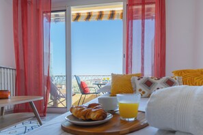 Un balcón con una mesa lista para el desayuno, que incluye cruasanes y jugo de naranja.