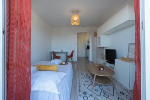 A hotel room with a bed, a desk, a television, and a kitchenette. - Sea view studio with private terrace & pool - Top floor on the Riviera (Villeneuve-Loubet)