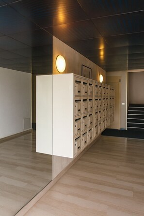 A hallway with lockers, a staircase, and a wall-mounted light fixture. - Sea view studio with private terrace & pool - Top floor on the Riviera (Villeneuve-Loubet)