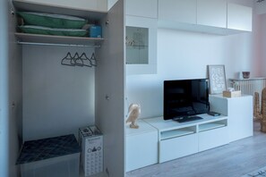A modern living space with a built-in TV, storage cabinets, and a radiator. - Sea view studio with private terrace & pool - Top floor on the Riviera (Villeneuve-Loubet)
