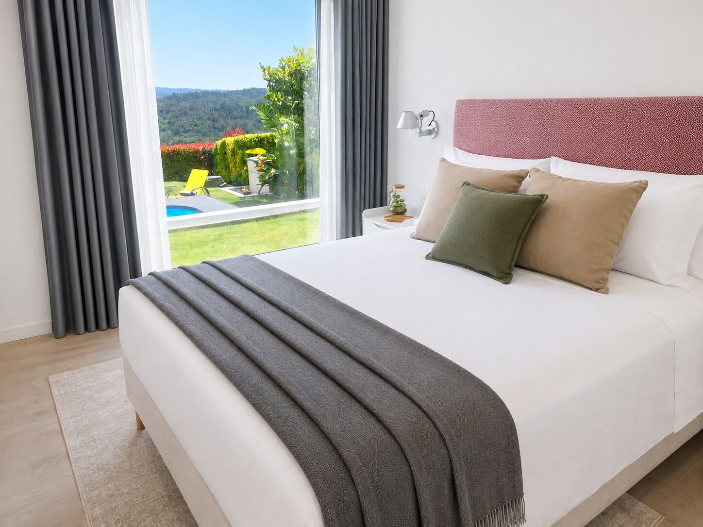 Une chambre avec un grand lit, une vue sur une piscine et un jardin, et une lampe sur la table de chevet.