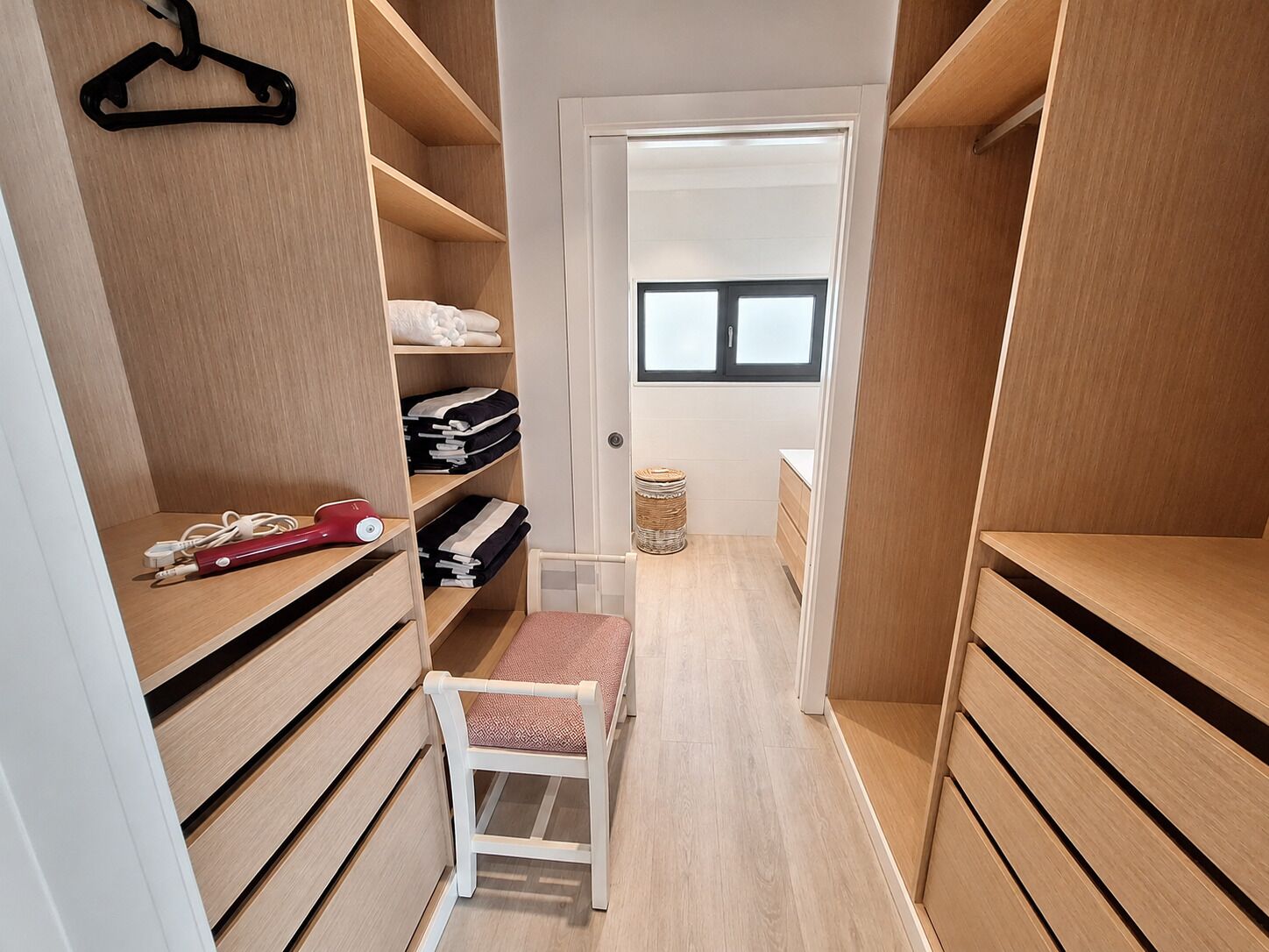 Armadio a muro con scaffalature in legno, una sedia e una finestra.