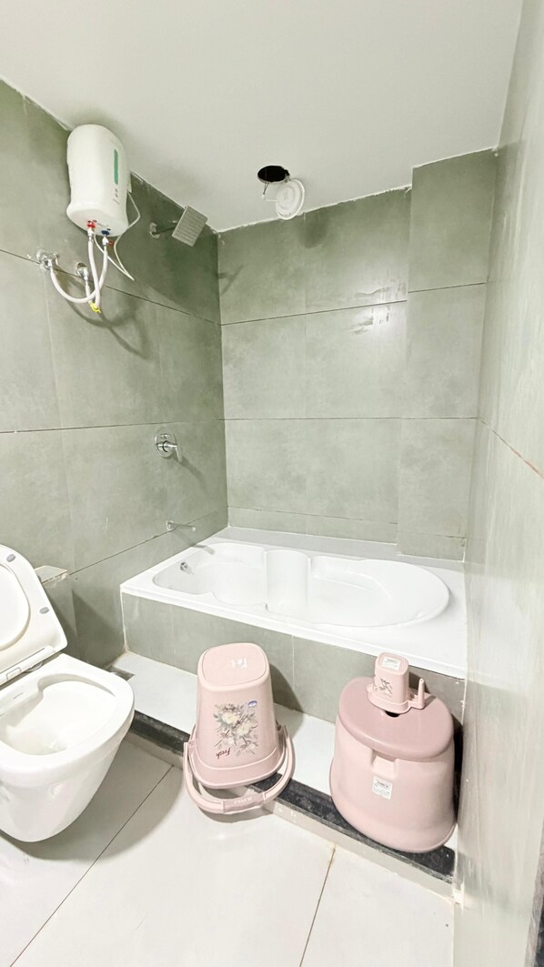 A bathroom with a bathtub, toilet, and bidet. - Hotel TGR Bharuch (Bharuch)