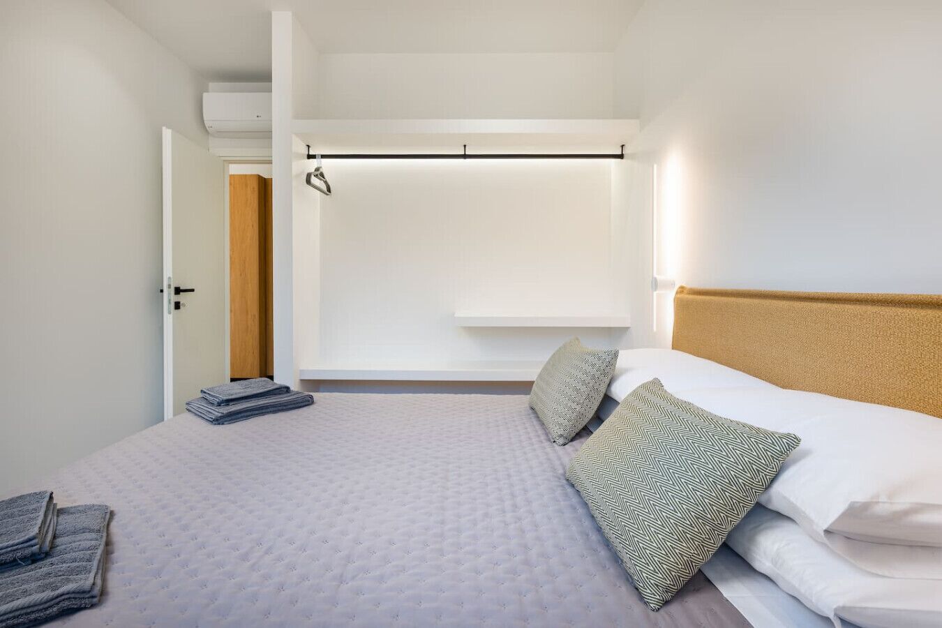 A bedroom with a bed, pillows, a hanging light fixture, and a door.