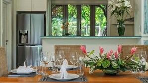 Un'area pranzo con tavolo apparecchiato per quattro persone, un frigorifero e una finestra che si affaccia sul verde.