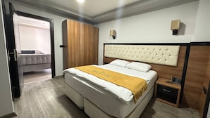 Habitació d'hotel amb llit, armari, taula de nit i porta que dona a una altra habitació.