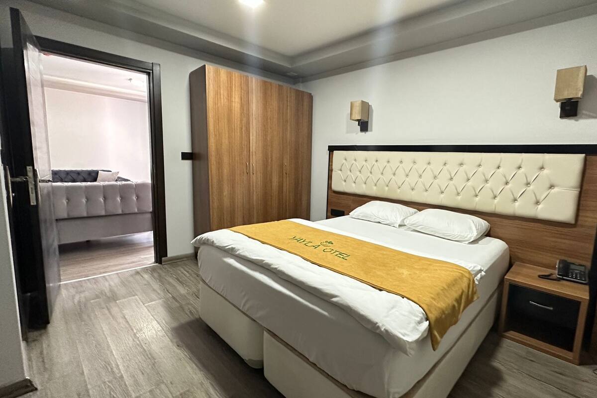 Une chambre d’hôtel comprenant un lit, une armoire, une table de chevet et une porte donnant sur une autre pièce.