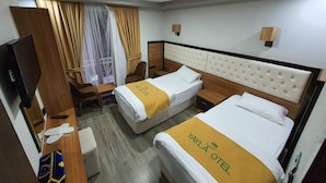 Habitació d'hotel amb dos llits, una taula de treball, una televisió i una finestra amb cortines.