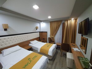 A hotel room with two beds, a desk, a chair, a TV, and a window with curtains. - YAYLA HOTEL UZUNGOL (Caykara)