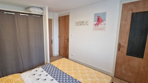 Een kamer met een bed, een houten deur, een muur met kunstwerken en een gordijn.