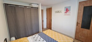Ein Zimmer mit einem Bett, einer Holztür, einer Wand mit Kunstwerken und einem Vorhang.
