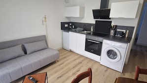 Een compact keukenhoekje met een wasmachine, een klein spoelgedeelte en een magnetron.