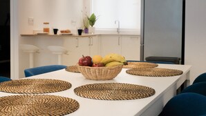 A dining table with a fruit basket, woven placemats, and blue chairs. - Nila 1 by Huskalia - City Center (Los Llanos de Aridane)