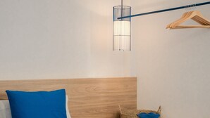 A bed with a wooden headboard, a blue pillow, a hanging light fixture, and a woven basket on a bedside table. - Nila 1 by Huskalia - City Center (Los Llanos de Aridane)