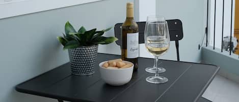 Una mesa pequeña con una botella de vino, una copa, un plato de galletas y una planta en maceta.