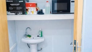 A bathroom with a sink, a microwave on the countertop, and toiletries.