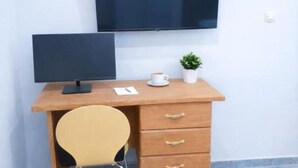 A wooden desk with a computer monitor, a cup, and a small plant.