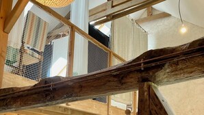 A loft-style room with exposed wooden beams, a hanging light fixture, a sofa, a small table, and a chair. - Gite modulable "Chez Yvette", 65m2 au calme à 800 mètres du centre ville (La Gacilly)