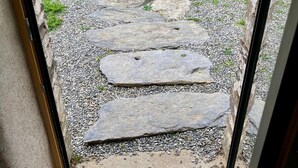 A stone pathway leading to a door with a doormat. - Gite modulable "Chez Yvette", 65m2 au calme à 800 mètres du centre ville (La Gacilly)